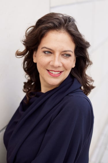 Eine Frau mit rotem Lippenstift schaut lächelnd über ihre Schulter.