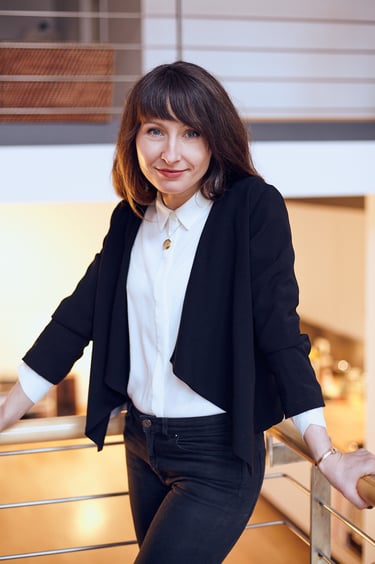 A young woman in black jeans and jacket leaning against a railing.
