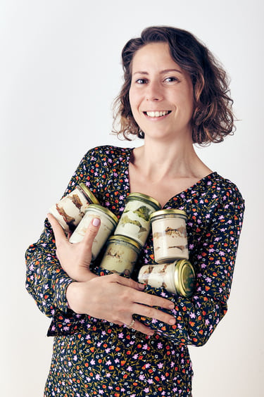 Smiling woman holding jars of tiramisu.
