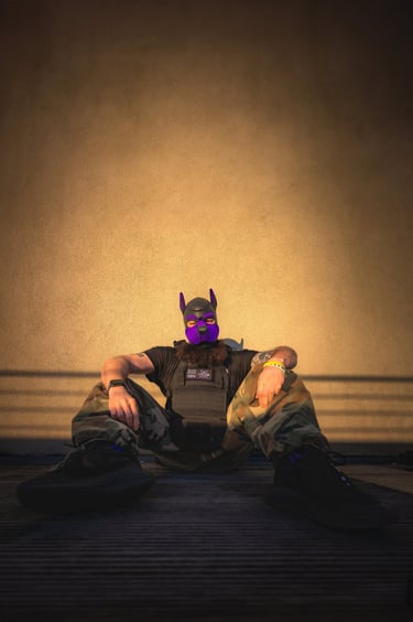 Man in pup mask sitting against a wall.