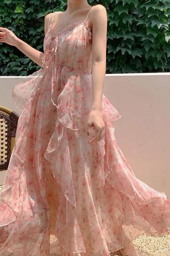 A woman wearing a light, flowy dress with small pink flowers and many large flowy layers.