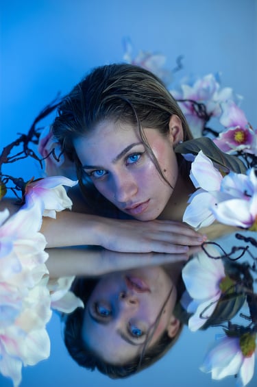 Modelo rubia con maquillaje de sirena, decorada con flores y gotitas de agua en estudio