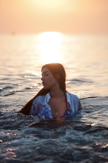 Modelo en la playa con vestido blanco y bikini a la vista, posando elegantemente