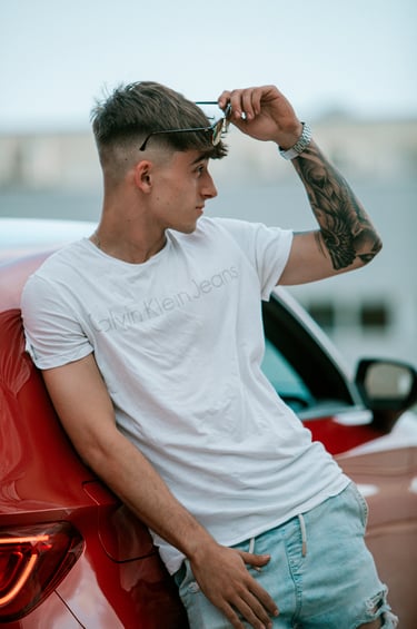 Plano abierto del modelo en una camiseta blanca Calvin Klein y un Seat León rojo