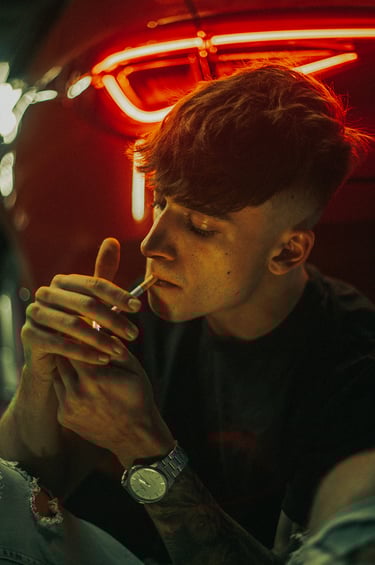 Fotografía artística de modelo fumando, destacando las luces rojas del coche