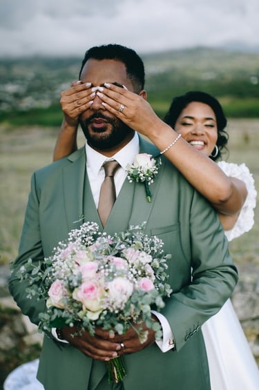 Mariée couvre les yeux du marié en costume vert sauge, first look champêtre.