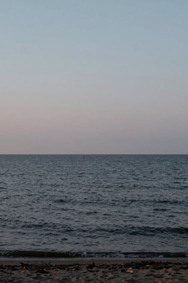 A minimalist landscape photography of the quiet Lake Ontario shoreline at dusk, near black water contrasting with a light grey sky, professional composition, capturing a sense of calm and reassurance.