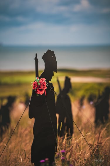 a man in a black suit and hat with a flower in his hand
