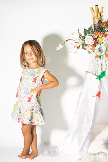 a little girl standing in front of a teepee