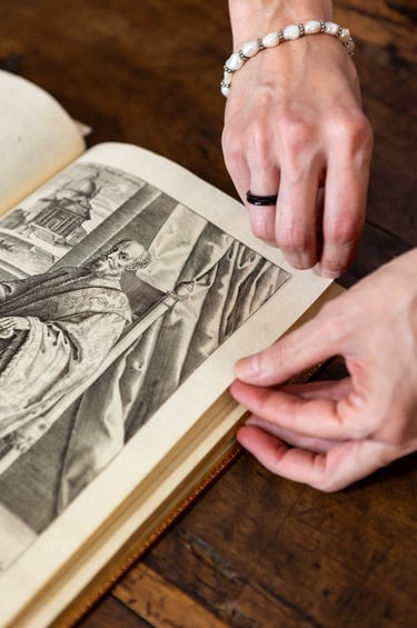 a woman is holding a book and pointing at a picture of a woman's
