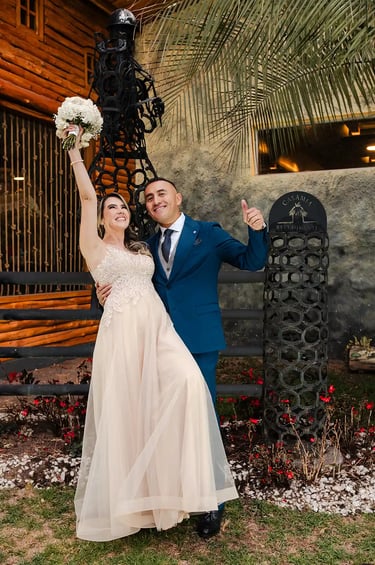 Recién casados celebrando sonriendo a cámara. La novia levanta el ramo y disfrutan de su momento juntos en Quito, Ecuador