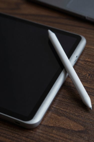 Close-up of a professional creative's workspace in Brazil, showing a black tablet and a light gray stylus on a dark wood texture. A subtle baby blue accent light glows from the side, creating a modern and innovative atmosphere.