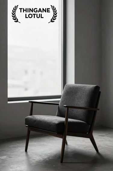 A sophisticated lifestyle photograph of an elegant, minimalist studio space featuring a single mid-century chair in dark charcoal, illuminated by a large window with luminous snow white light.