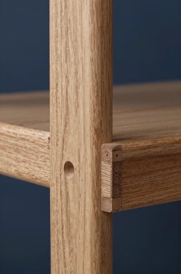 A minimalist close-up photograph of a custom-designed wooden furniture detail, showcasing precision joints and technical craftsmanship. The light oak wood contrasts beautifully against a deep navy blue background. Soft, diffused lighting emphasizes the clean lines and sophisticated texture in a Northern European style.