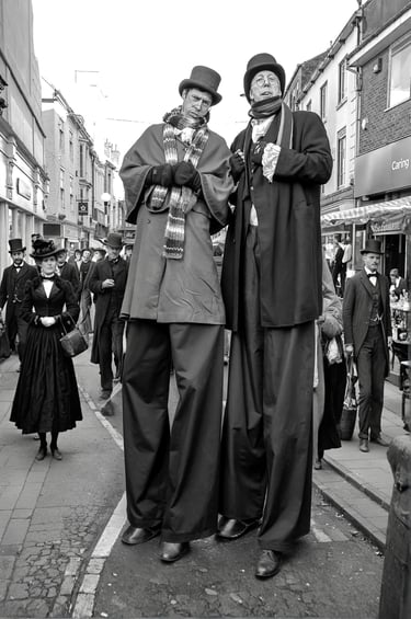 Performers in Victorian / Edwardian costumes on stilts at a Dickens festival street event.