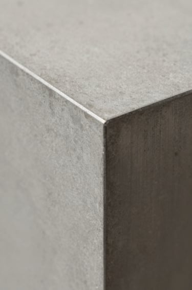 A detail-oriented close-up of high-quality architectural materials. A combination of smooth concrete and brushed #2F2E2E steel panels. The shot focuses on the precision of the joints and the play of soft shadows on #D9D2C7 textures, conveying a sense of quality and confidence.