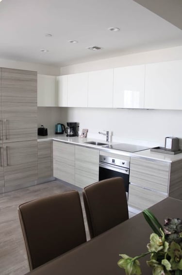 Modern minimalist kitchen with light wood grain cabinets, white upper units, and built-in appliances.