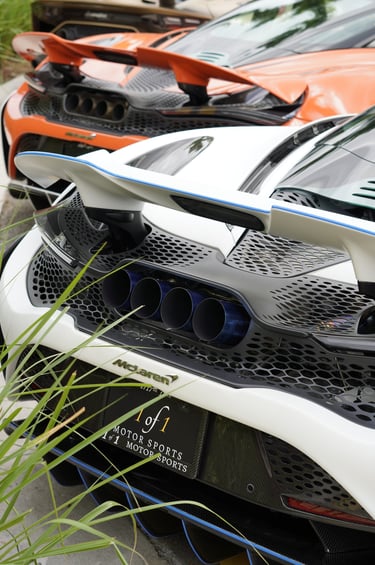 Rear view of a white McLaren 765LT featuring quad titanium exhaust tips and carbon fiber aerodynamic wing.