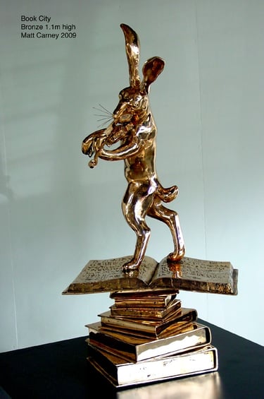 a bronze statue of a rabbit on a stack of books playing the violin