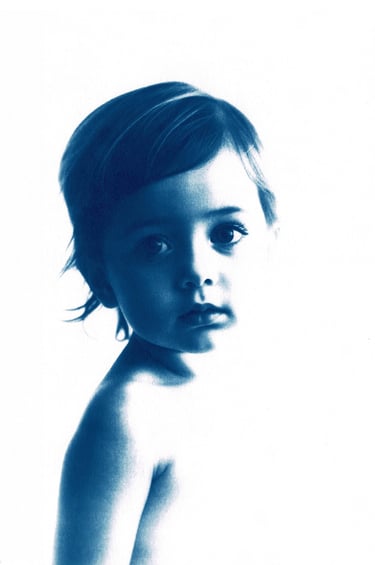 Monochromatic blue portrait of a little girl with short, tousled hair, expressive eyes, and a serene