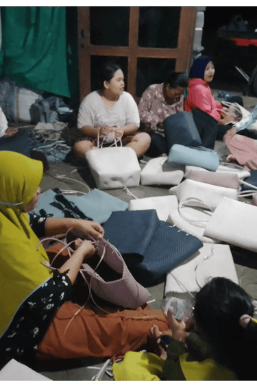 Group of artisans crafting handmade woven plastic bags together at Craftvitas Indonesia production area.