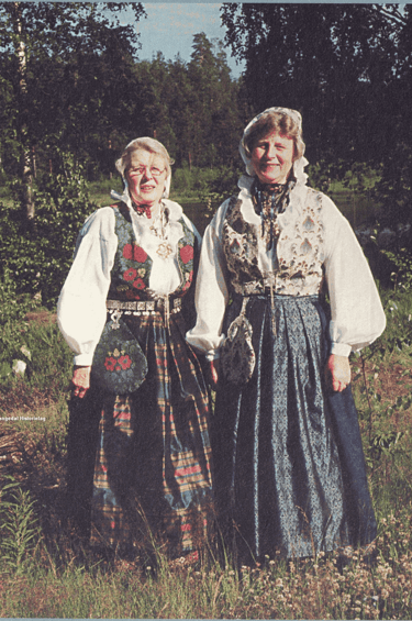Two women stand in a meadow in traditional dress