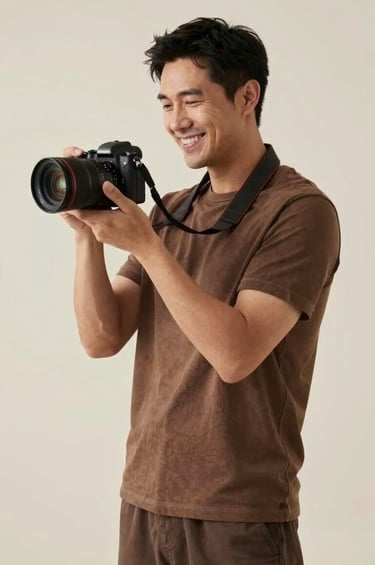 A professional and approachable portrait of a photographer with a warm expression, holding a modern camera and standing in a minimalist studio with soft light in North American / US. The palette is dominated by cream and dark brown.