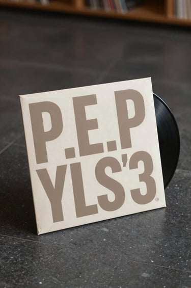 A striking visual of a vinyl record in a sleeve that features bold, modern typography and Nigerian patterns in #8D765D. The image is shot from a low angle on a clean, dark stone floor to emphasize P.E.P YLS's premium brand status. Soft ambient light creates a moody, immersive atmosphere.