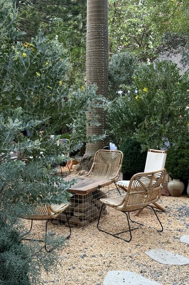 Rattan-style outdoor chairs surrounded by lush greenery, showing how woven materials add softness to