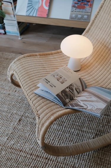 Cozy balcony reading corner with comfortable outdoor chair, small side table, warm lighting, plants,
