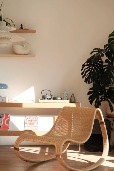 Cozy balcony reading corner with comfortable outdoor chair, small side table, warm lighting, plants,