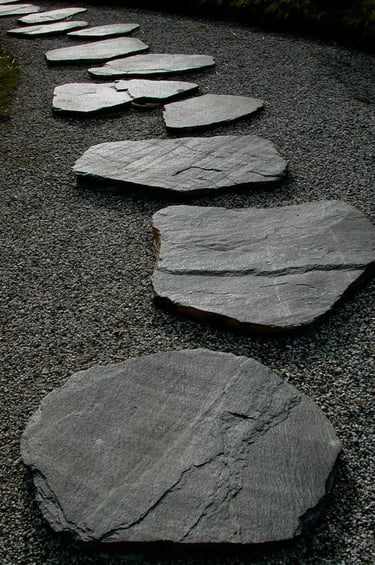 Dark stone stepping path with natural slate slabs and gravel, creating a quiet and timeless garden w