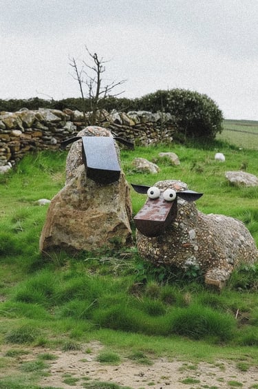 Rustic stone sheep sculptures in a grassy garden field, adding character, texture and natural charm