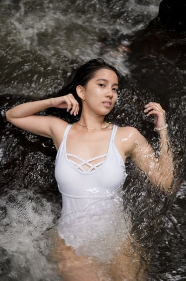 Close portrait of woman lying in flowing water during photoshoot at Kanto Lampo Bali