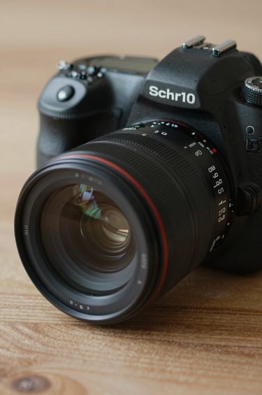 A professional DSLR camera placed on a textured wooden surface, capturing the photographer's gear in a storytelling style. Soft side-lighting emphasizes the lens glass. The mood is professional and ready for action, using a color palette of #0D0D0D and #8C847E.