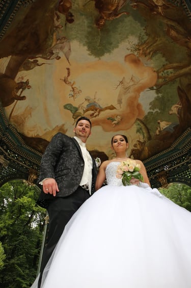 a bride and groom standing in front of a painted ceiling