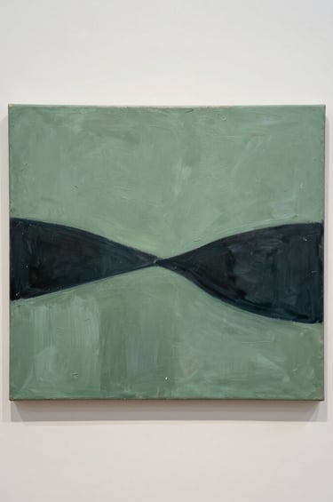 A minimalist gallery scene in a North American setting. On an off-white wall hangs a textured acrylic on canvas painting featuring sage green and dark charcoal abstract forms. The composition is clean and artistic, captured with professional gallery lighting.