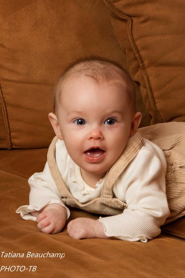 Photo d'un adorable bébé aux yeux bleus, allongé sur le ventre et souriant