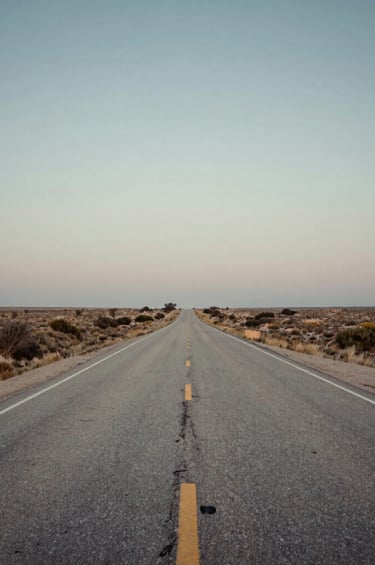 A scenic view of a dusty North American highway stretching toward the horizon at dusk, capturing the spirit of an Americana road trip. Soft, nostalgic, and inviting wide-angle photography. Colors include slate blue-grey, off-white, and copper.