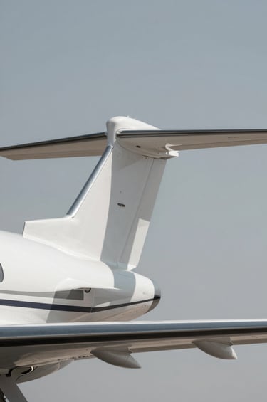 A minimalist, low-angle shot of a private jet's winglet against a crisp, cloudless sky in #F8F8F8. The wing surface is a smooth #B2BEB5, with sharp geometric shadows in #1C2833. Modern, exclusive, and precise visual storytelling.