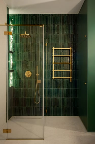 Realizacja łazienki: strefa prysznica, zieleń i złoty grzejnik.