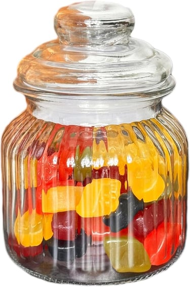 A clear ribbed glass apothecary jar filled with colorful gummy bears on a white background.