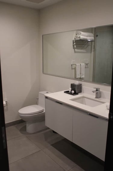Modern hotel bathroom featuring a white floating vanity, large mirror, and contemporary toilet.
