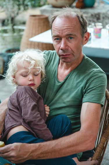 Un homme porte son fils sur ses genoux avec tendresse, par Zohra Elmes