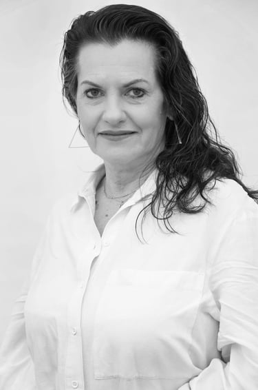 Professional black and white portrait of a woman with dark wavy hair wearing a white button-down shirt.
