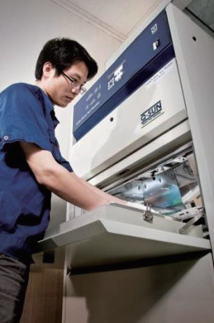 A technician operates a Q-SUN Xenon Test Chamber for accelerated weathering and lightfastness testing.