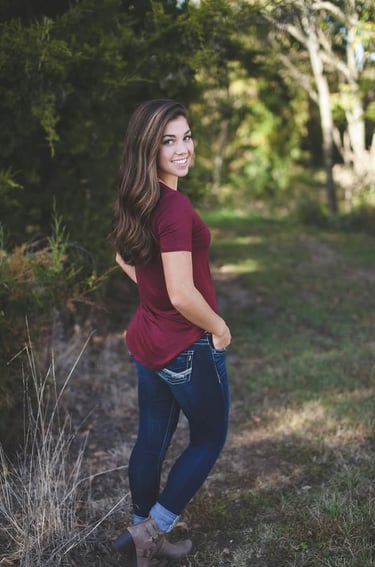 a woman in jeans and a maroon shirt is posing for a photo
