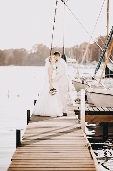 Brautpaar küsst sich auf einem Steg am Möhnesee bei Sonnenlicht – romantischer Moment eingefangen vom Hochzeitsfotografen am