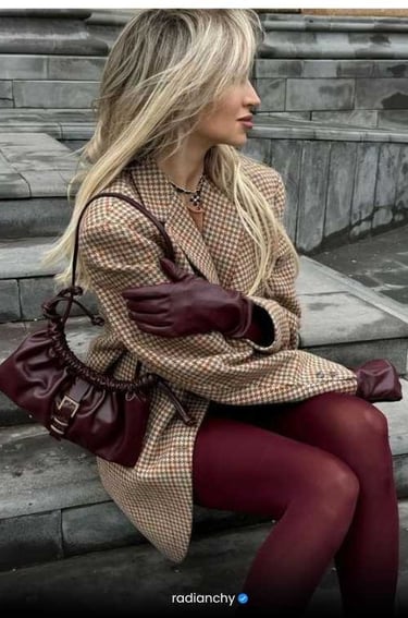a woman in a coat and gloves sitting on a bench