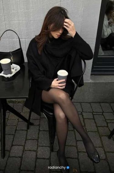a woman sitting at a table with a cup of coffee